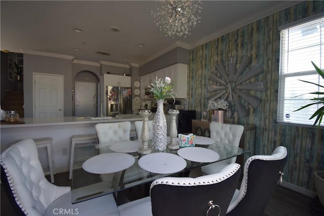 dining area featuring crown molding, sink, a notable chandelier, and hardwood / wood-style flooring