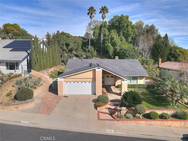 view of front facade with stucco siding, an attached garage, driveway, and fence