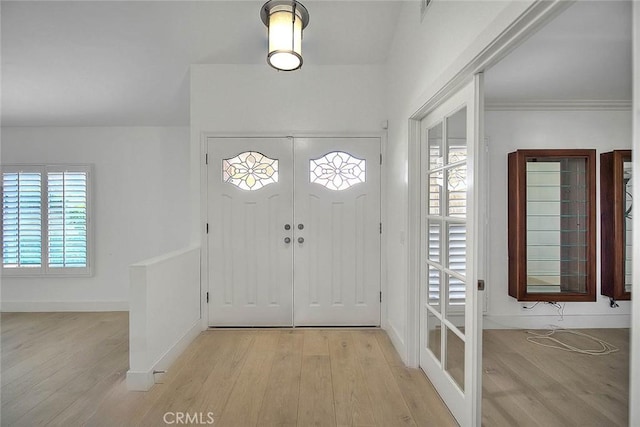 foyer entrance with baseboards, plenty of natural light, ornamental molding, and light wood finished floors