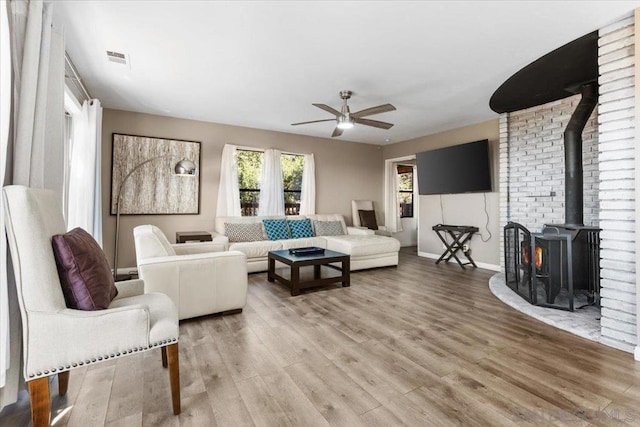 living room featuring hardwood / wood-style flooring, a wood stove, and ceiling fan