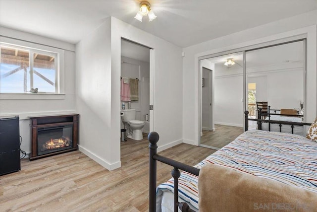 bedroom featuring ensuite bath, light hardwood / wood-style floors, and a closet