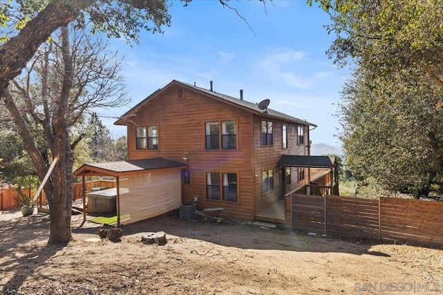 rear view of house featuring central AC and a jacuzzi