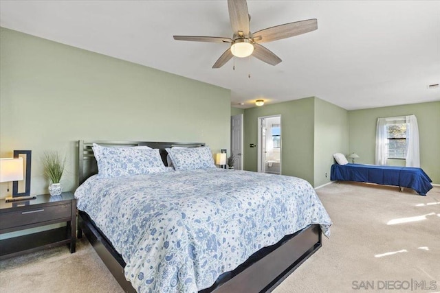 bedroom featuring connected bathroom, light colored carpet, and ceiling fan