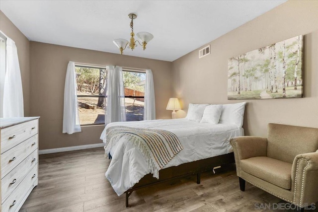 bedroom with hardwood / wood-style flooring and a notable chandelier