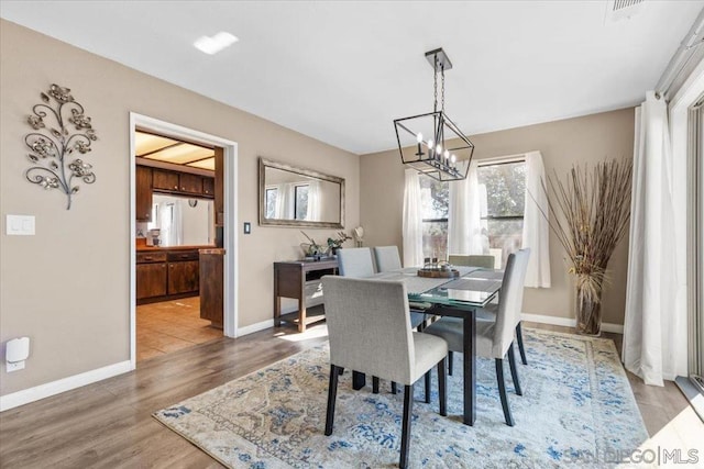 dining space with hardwood / wood-style flooring and a notable chandelier