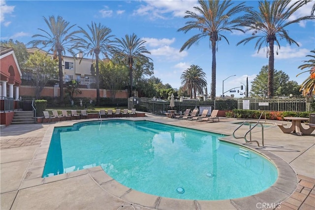 community pool with a patio and fence
