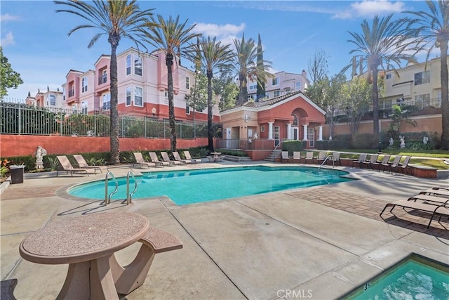 community pool with a patio and fence