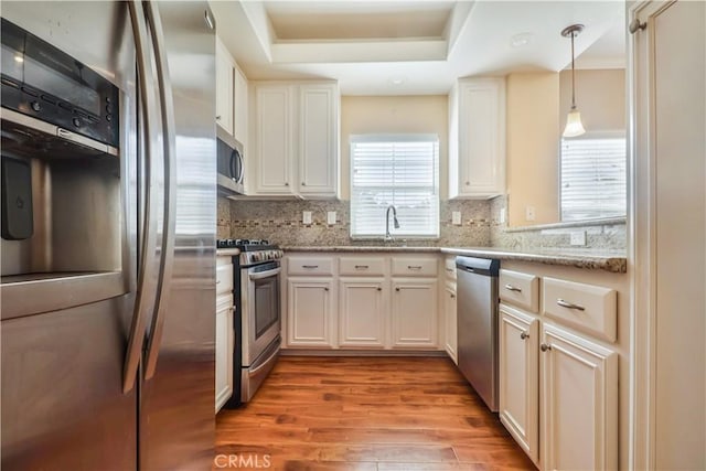 kitchen with stainless steel appliances, white cabinetry, and light stone counters