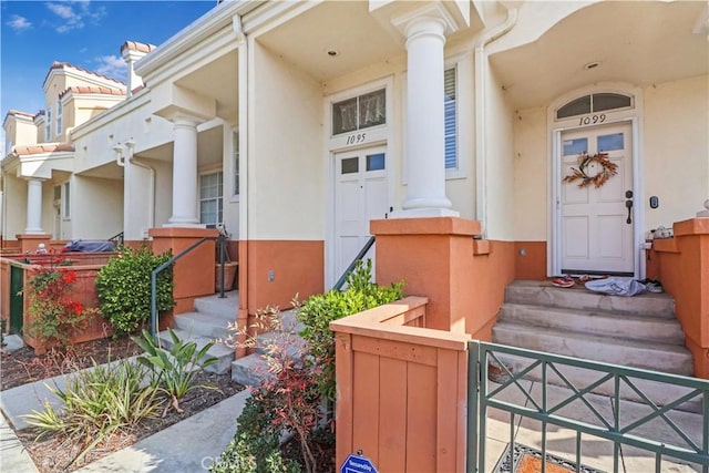 entrance to property featuring stucco siding and fence