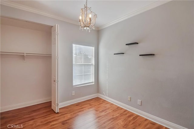 unfurnished bedroom featuring ornamental molding, wood-type flooring, multiple windows, and a notable chandelier