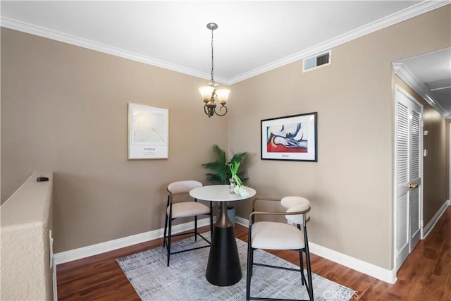 dining room featuring baseboards, attic access, crown molding, visible vents, and wood finished floors
