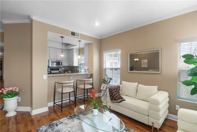 living area with wood finished floors, baseboards, and visible vents