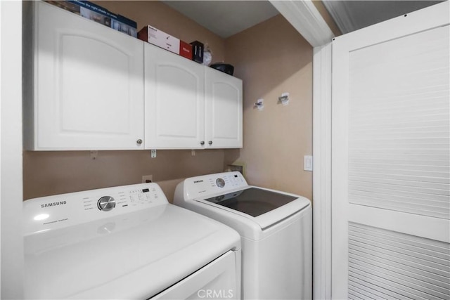 laundry room featuring washing machine and clothes dryer and cabinet space