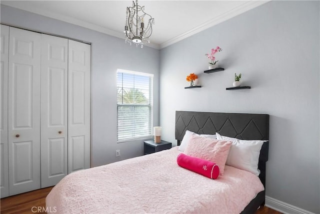 bedroom featuring a chandelier, crown molding, a closet, and dark wood-style flooring