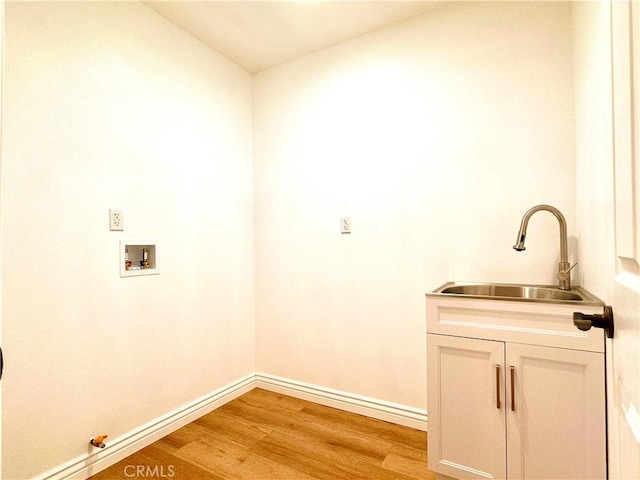 laundry room with hookup for a washing machine, sink, cabinets, and light wood-type flooring