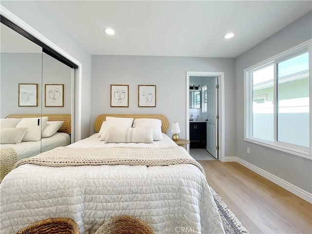 bedroom featuring connected bathroom, light hardwood / wood-style floors, and a closet