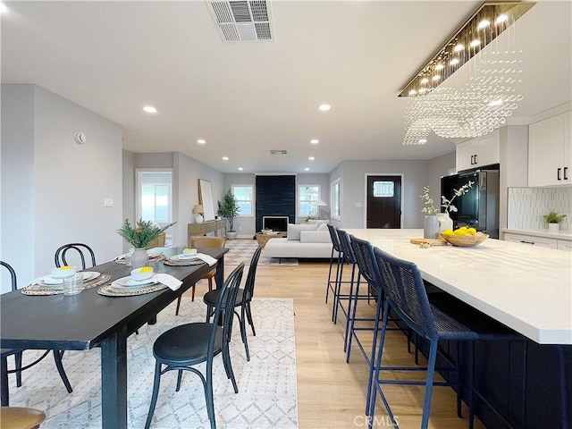 dining space featuring a large fireplace, a healthy amount of sunlight, and light wood-type flooring