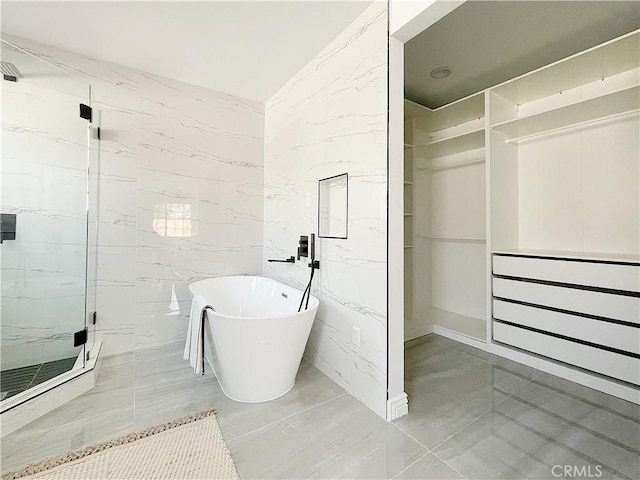 bathroom with shower with separate bathtub and tile walls