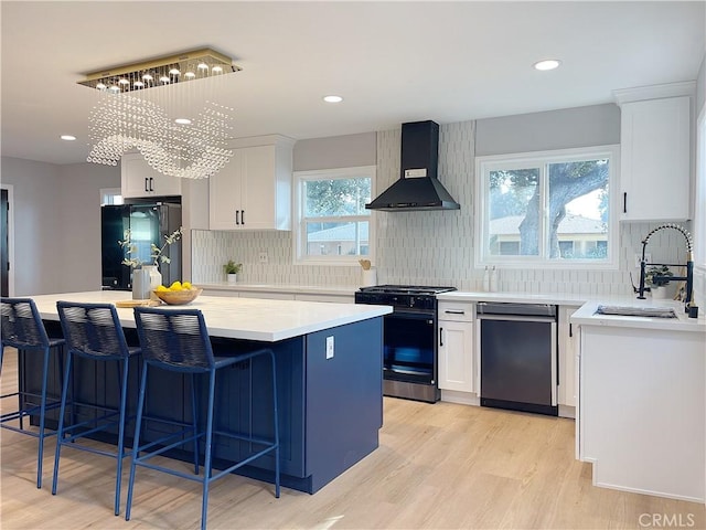 kitchen with sink, a center island, black appliances, white cabinets, and wall chimney exhaust hood