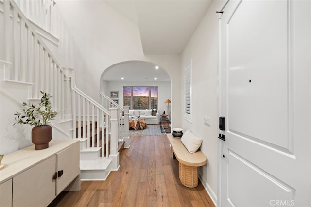 foyer entrance with light wood-style floors, stairway, arched walkways, and recessed lighting