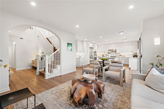 living room with light wood-style floors, recessed lighting, and stairs