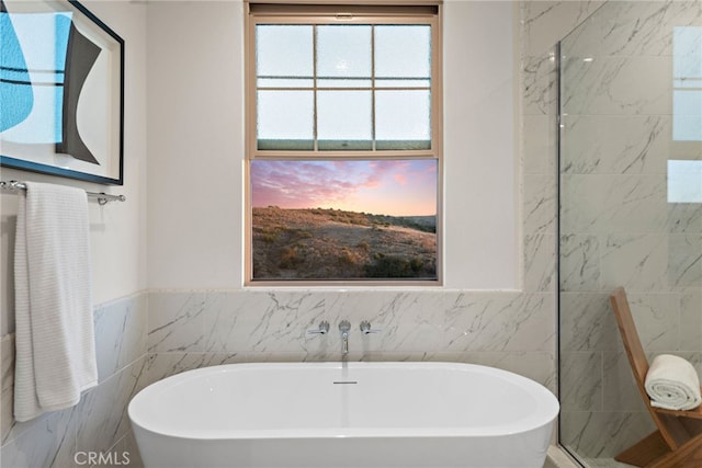 full bathroom with a soaking tub and tile walls