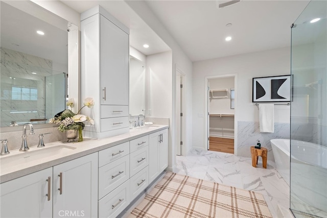 bathroom featuring a freestanding bath, double vanity, a sink, and recessed lighting