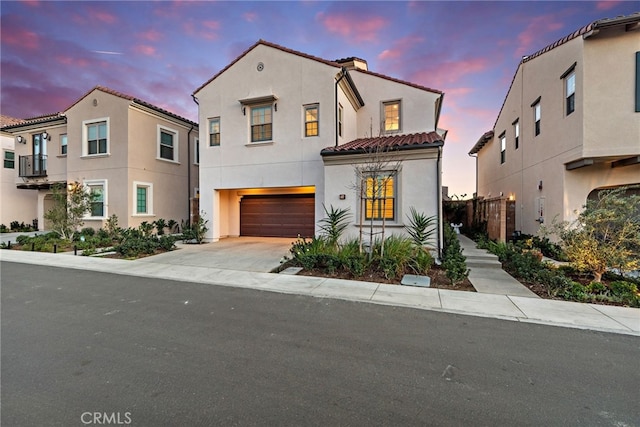 mediterranean / spanish house with concrete driveway, an attached garage, a tile roof, and stucco siding