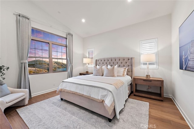 bedroom with multiple windows, vaulted ceiling, and wood finished floors