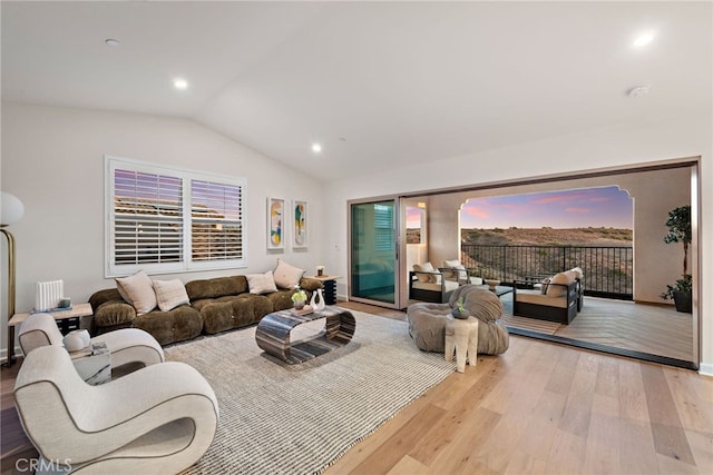 living room featuring lofted ceiling, light wood-style flooring, and recessed lighting