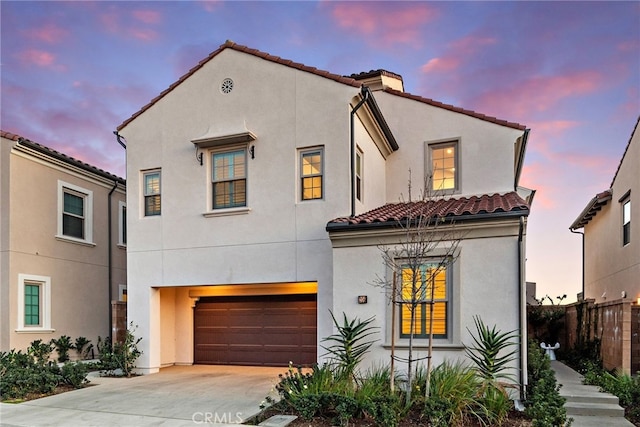 mediterranean / spanish house featuring a garage, fence, a tiled roof, concrete driveway, and stucco siding