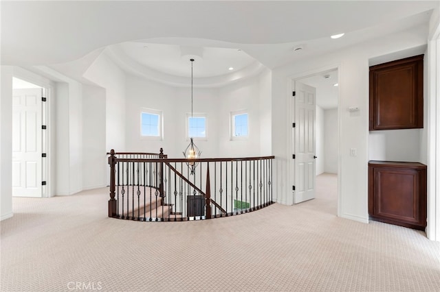 corridor with light colored carpet and a tray ceiling