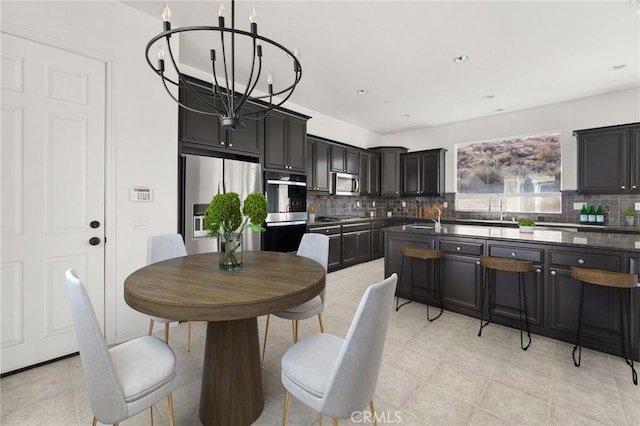 kitchen featuring sink, backsplash, a chandelier, light tile patterned floors, and stainless steel appliances