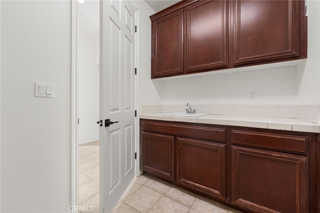 interior space with tile countertops, sink, and light tile patterned floors