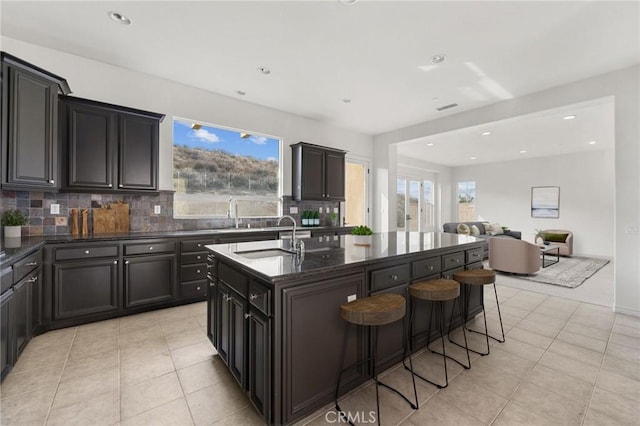 kitchen with a kitchen bar, a healthy amount of sunlight, sink, and a kitchen island with sink