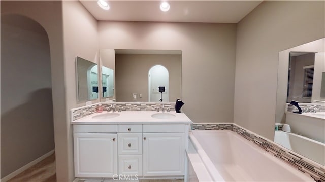 bathroom with a tub to relax in, vanity, and backsplash