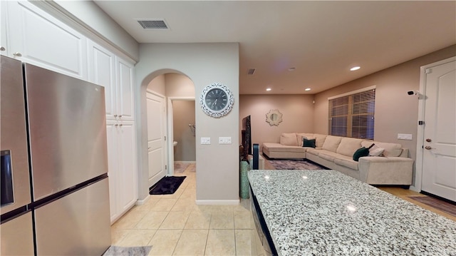 kitchen featuring white cabinetry, light tile patterned floors, light stone countertops, and stainless steel refrigerator with ice dispenser