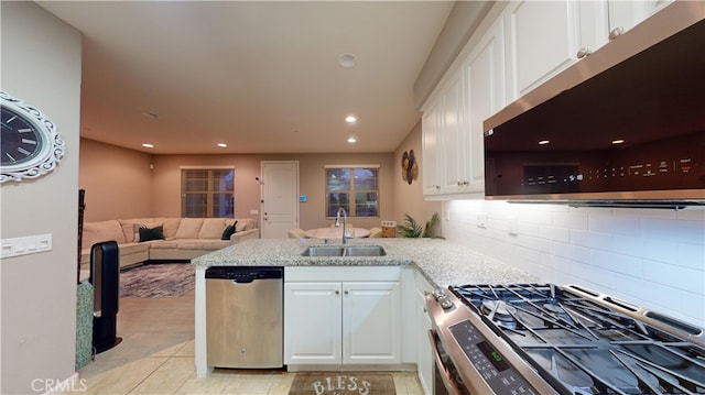 kitchen with appliances with stainless steel finishes, sink, white cabinets, light tile patterned floors, and kitchen peninsula