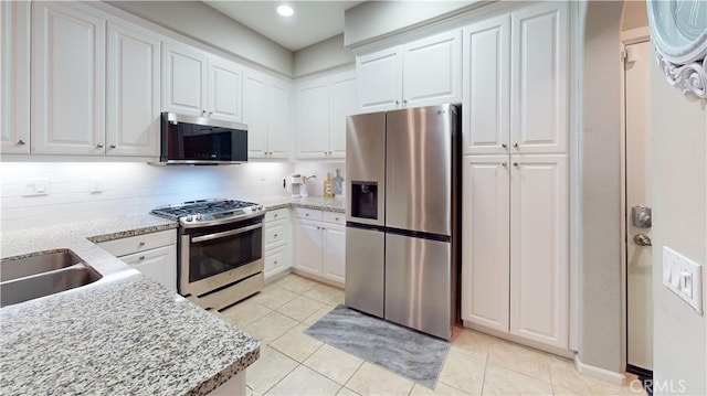 kitchen featuring white cabinetry, tasteful backsplash, appliances with stainless steel finishes, and light stone counters