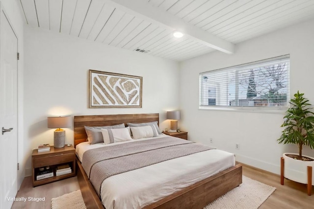 bedroom with beamed ceiling and light hardwood / wood-style flooring