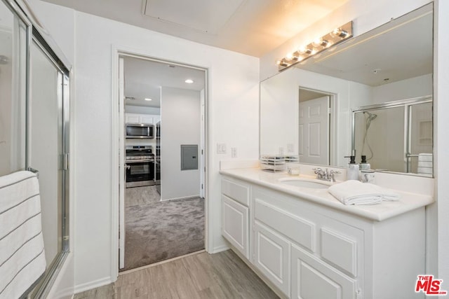 bathroom with vanity, hardwood / wood-style floors, and bath / shower combo with glass door