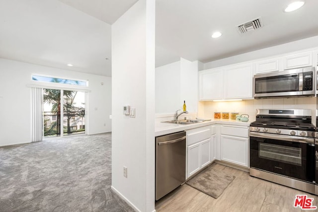 kitchen featuring white cabinetry, appliances with stainless steel finishes, sink, and light carpet