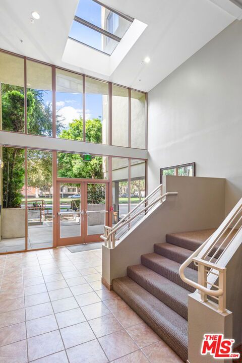 stairway featuring tile patterned floors, plenty of natural light, a wall of windows, and a high ceiling