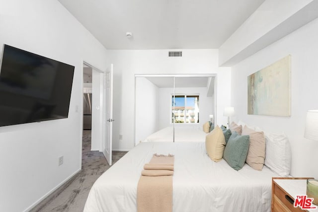 bedroom with stainless steel refrigerator, a closet, and carpet