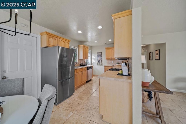 kitchen featuring light tile patterned flooring, black refrigerator, dishwasher, decorative backsplash, and light brown cabinets