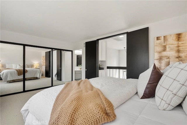 bedroom featuring ensuite bath, light colored carpet, and a closet