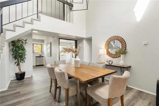 dining space with wood-type flooring and a high ceiling