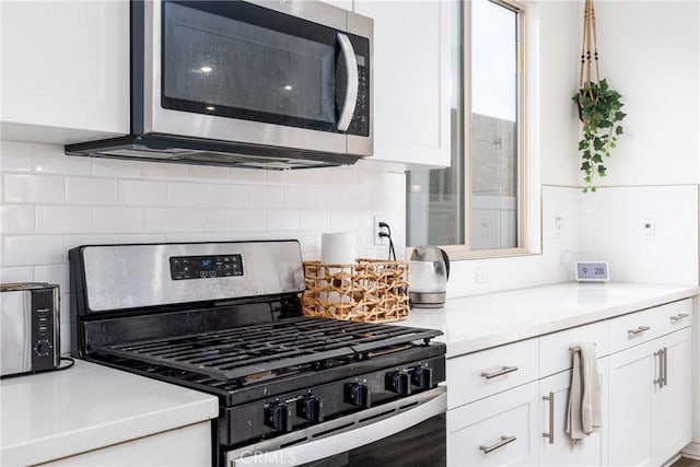 kitchen with backsplash, stainless steel appliances, and white cabinets