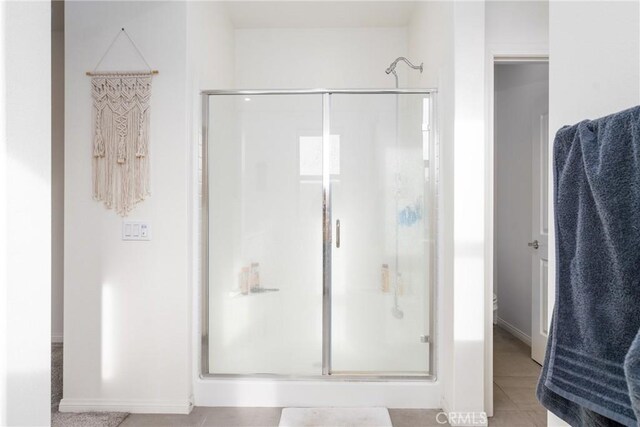 bathroom with an enclosed shower and tile patterned floors