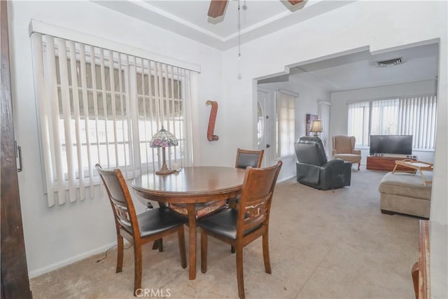 dining space with light carpet and ceiling fan